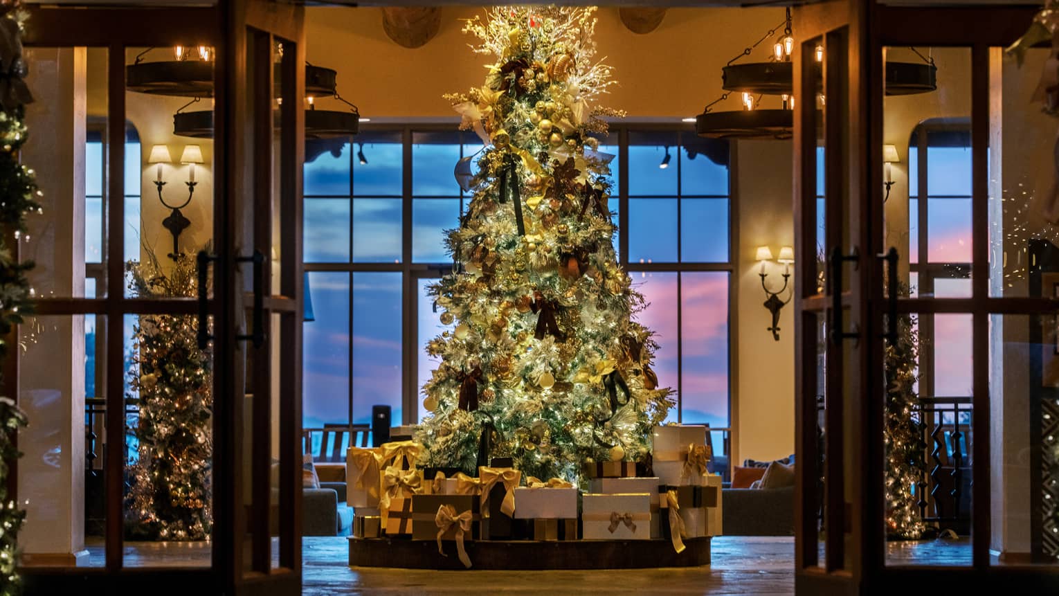 A tree decorated with lights and ornaments and surrounded by presents