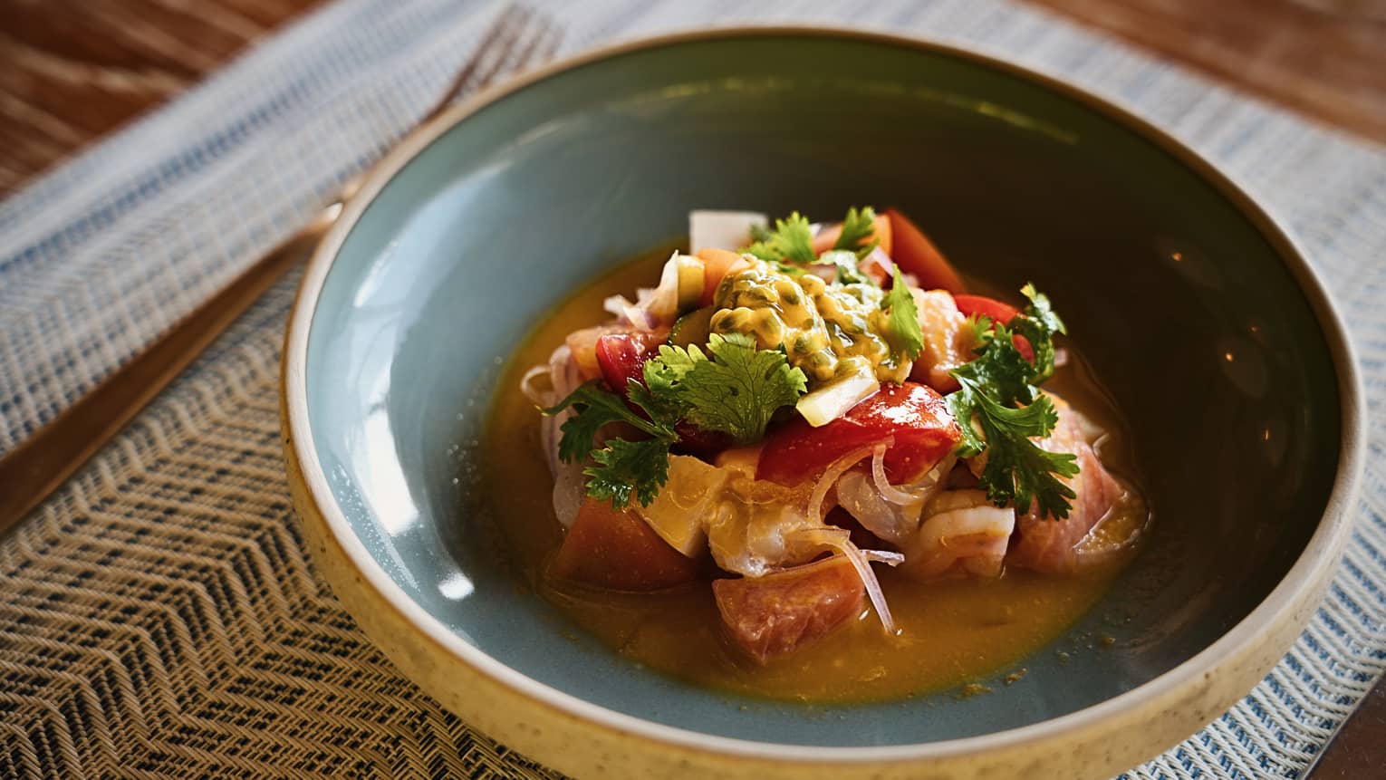 A shallow round bowl with light-blue glazed interior holds colourful food items.