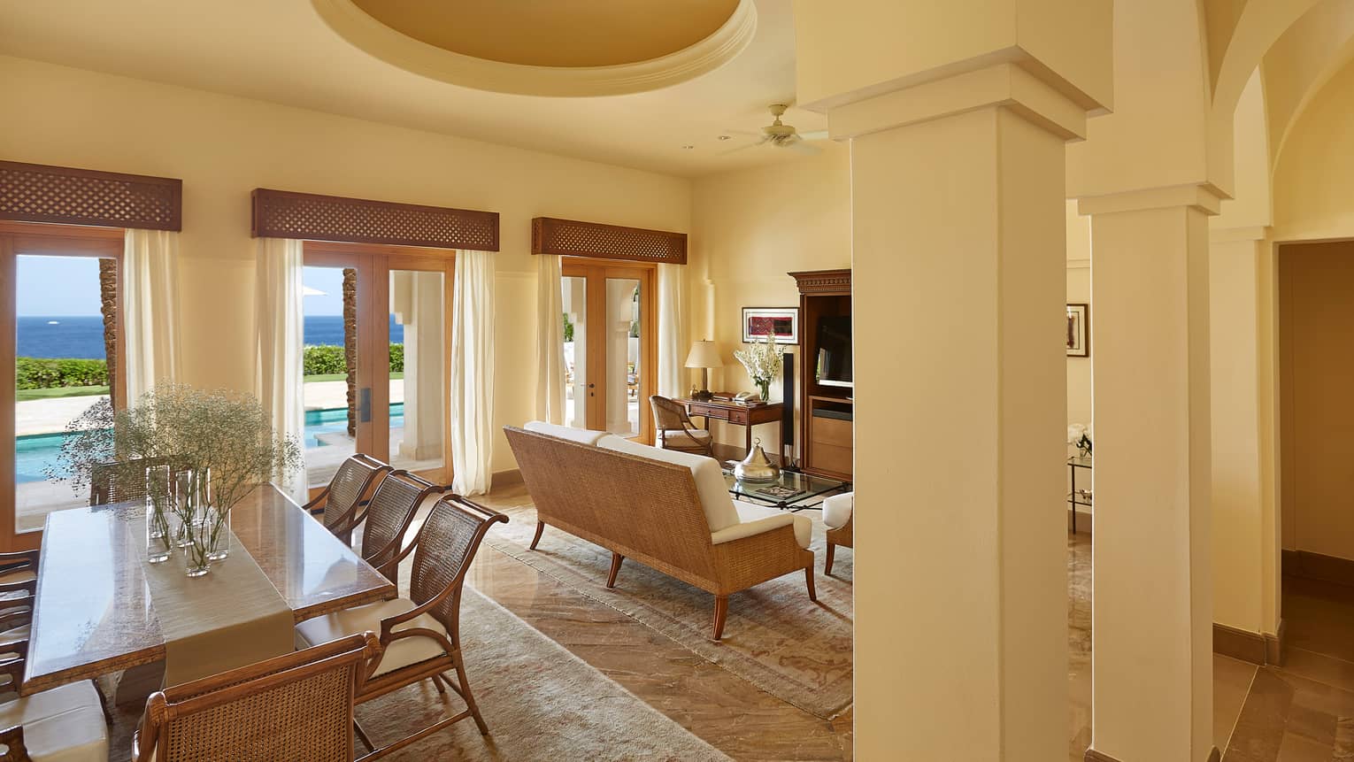 Presidential Suite dining area, living room under white recessed ceiling, pillars, large balcony doors to pool