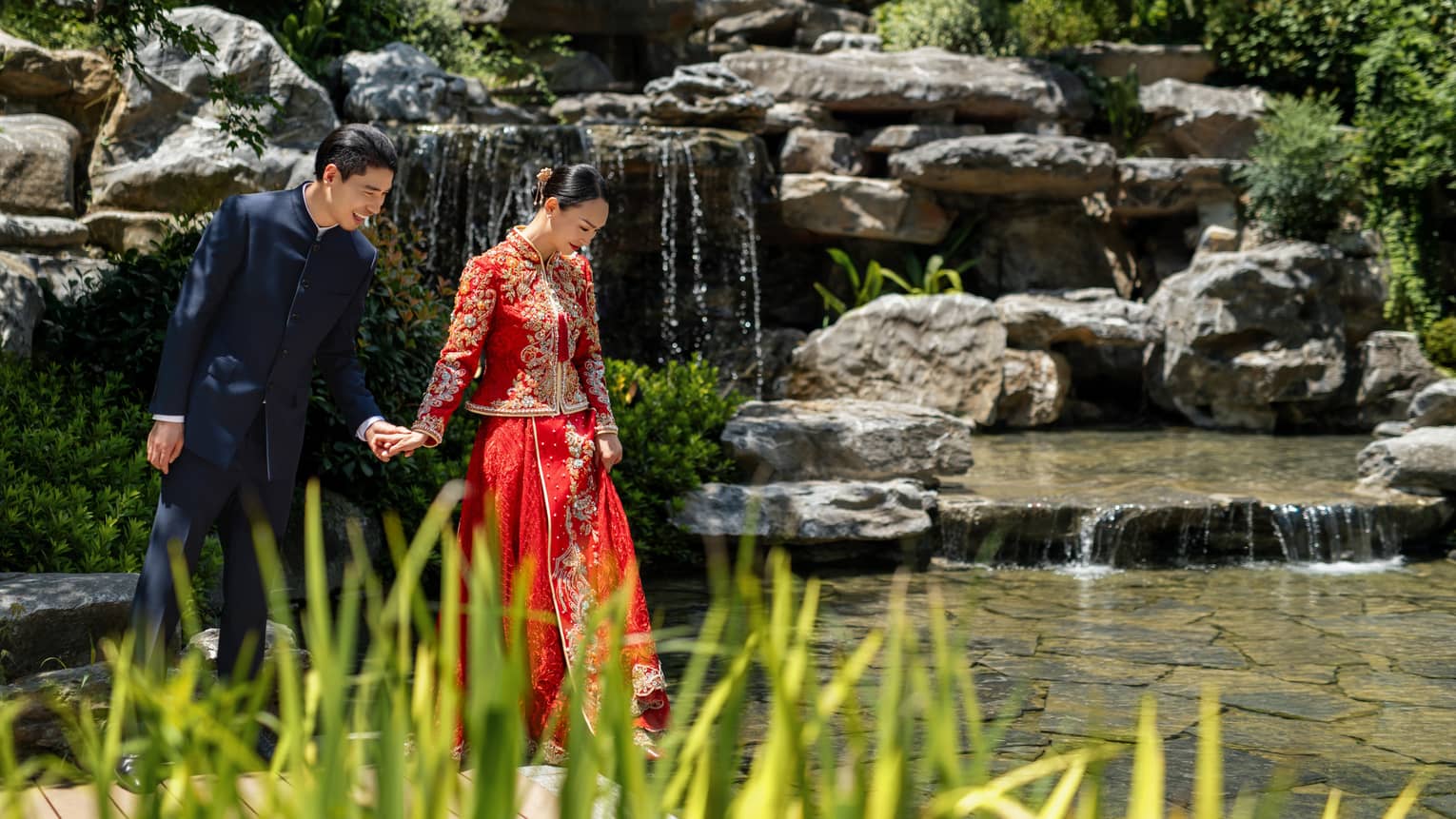 Mand and woman walk together in a garden with waterfall