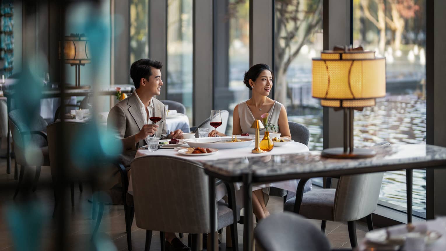 Man and woman dine at fine dining Chinese restaurant by the window with a pool view