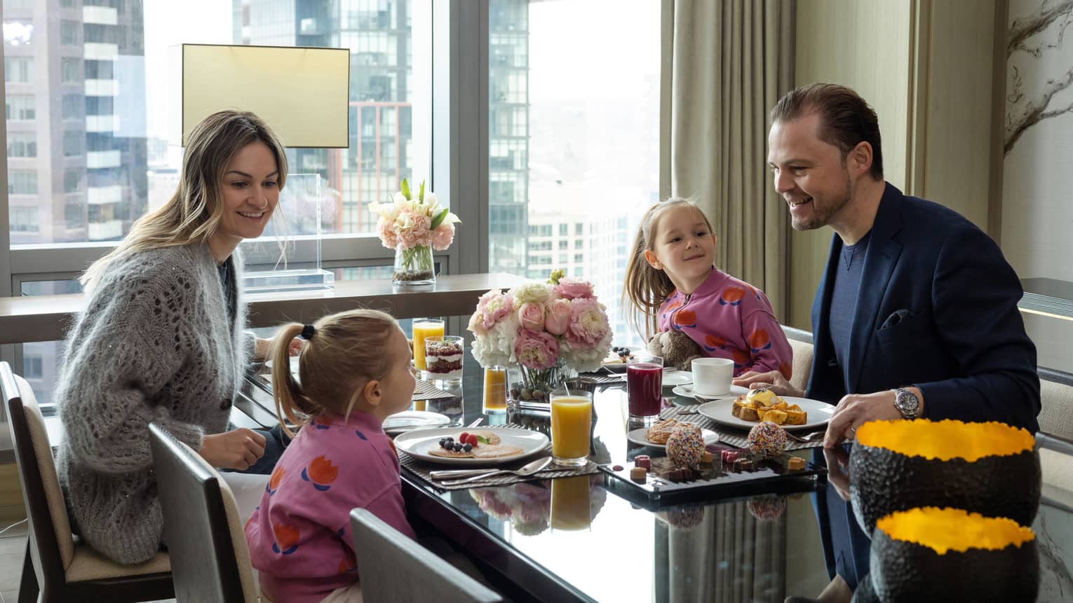 A family of four sits at a black table overlooking the Toronto cityscape.