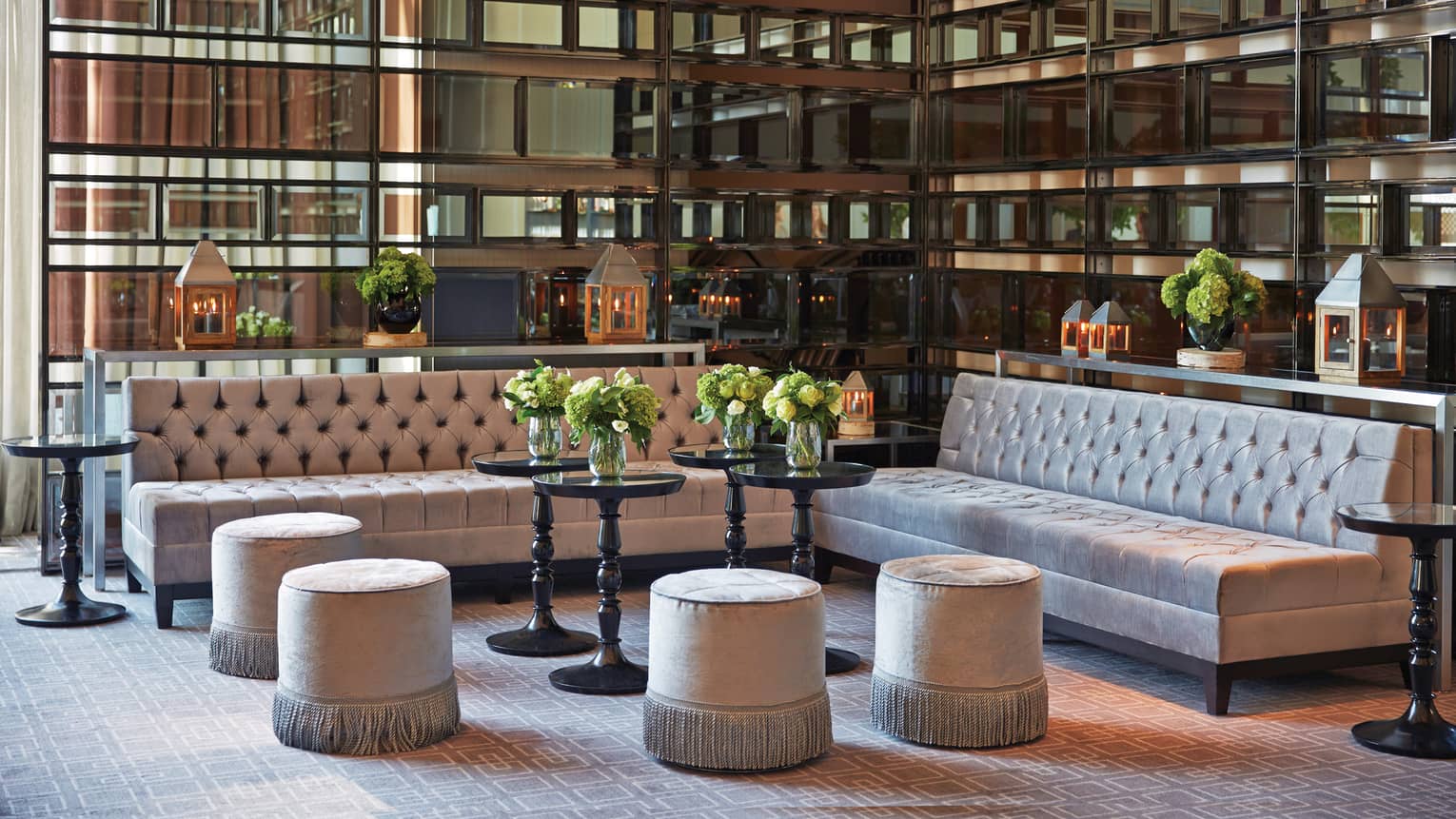 Aria room with velvet sofas, ottomans under decorative corner glass windows 