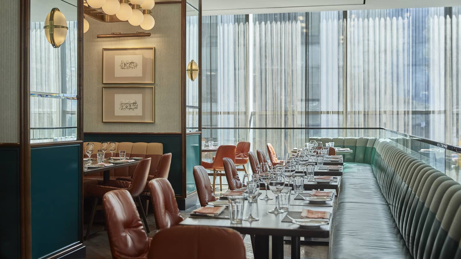 Blue upholstered sofas and brown chairs at a set table, floor length windows, round lights