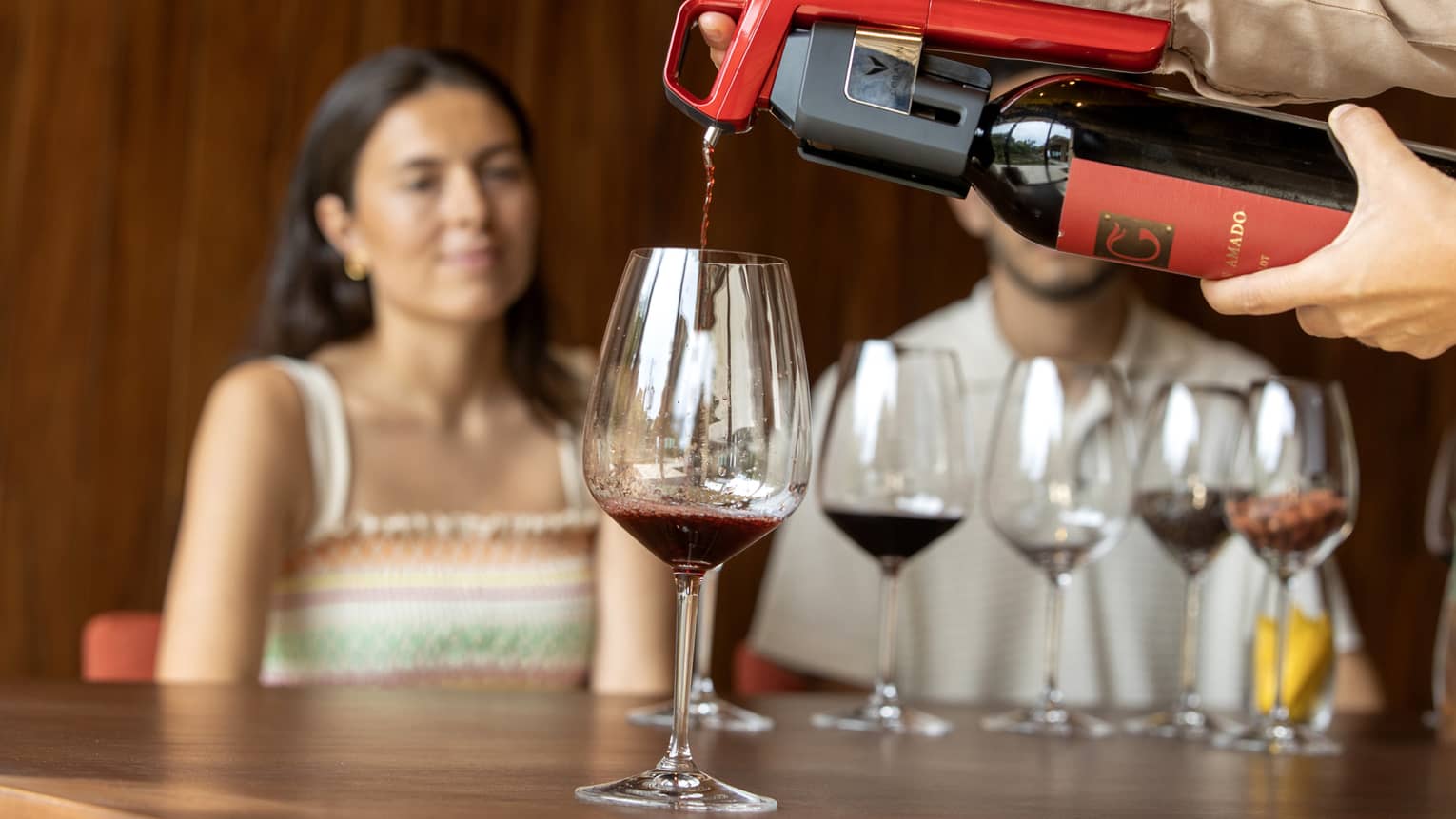 A glass of red wine is poured in front of a couple doing a wine tasting