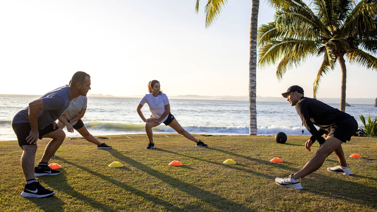 Four guests doing a fitness workout outside near the ocean