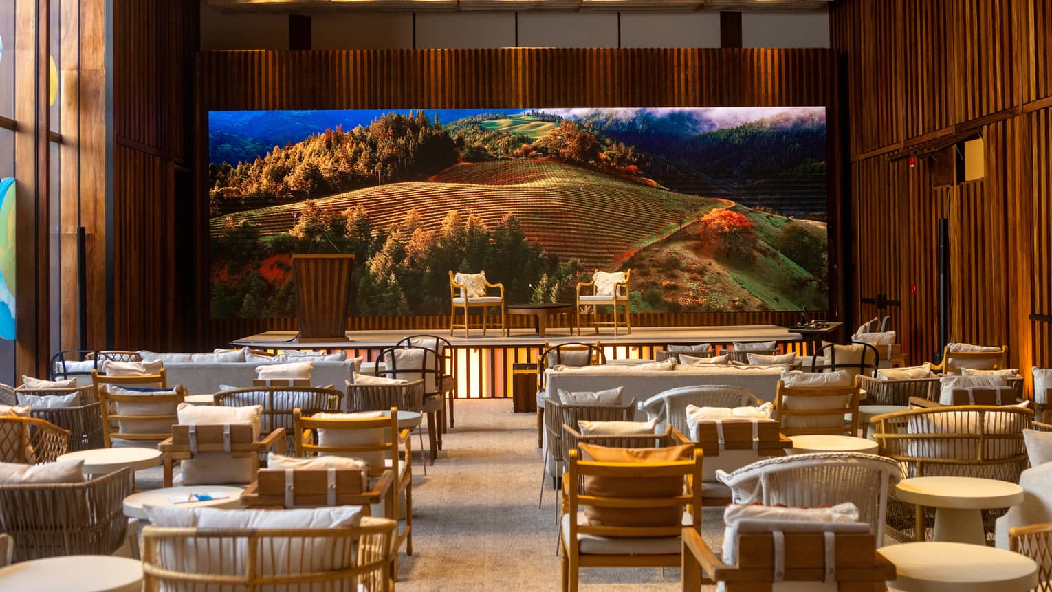 Event room with a stage and screen with image of mountain and trees.