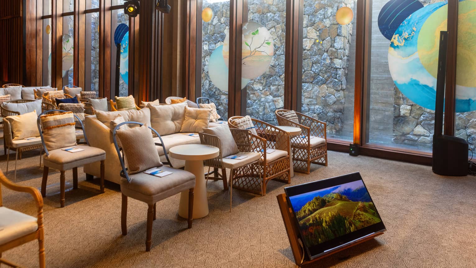 Room with floor to ceiling windows and rows of chairs and couches with a view of a staircase.
