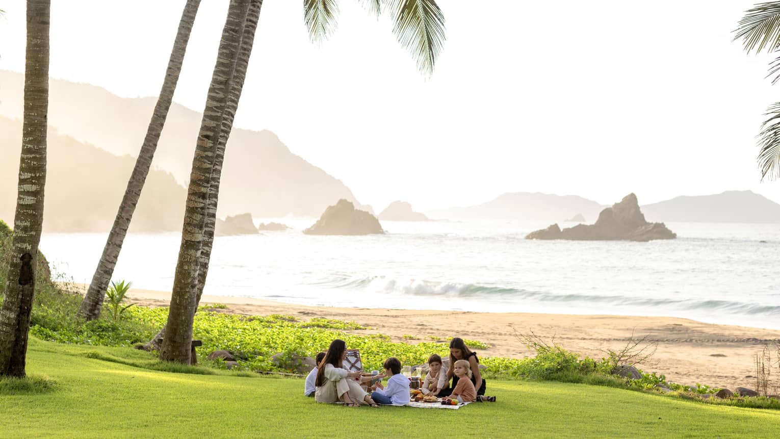 Many guests having a picnic surrounded by palm trees.
