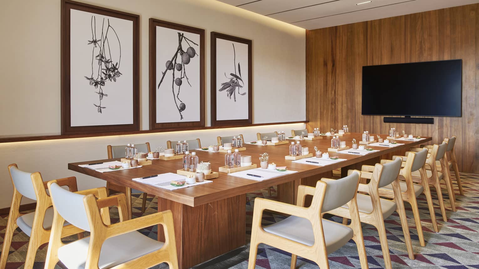 Boardroom with wooden table and three paintings on the wall.