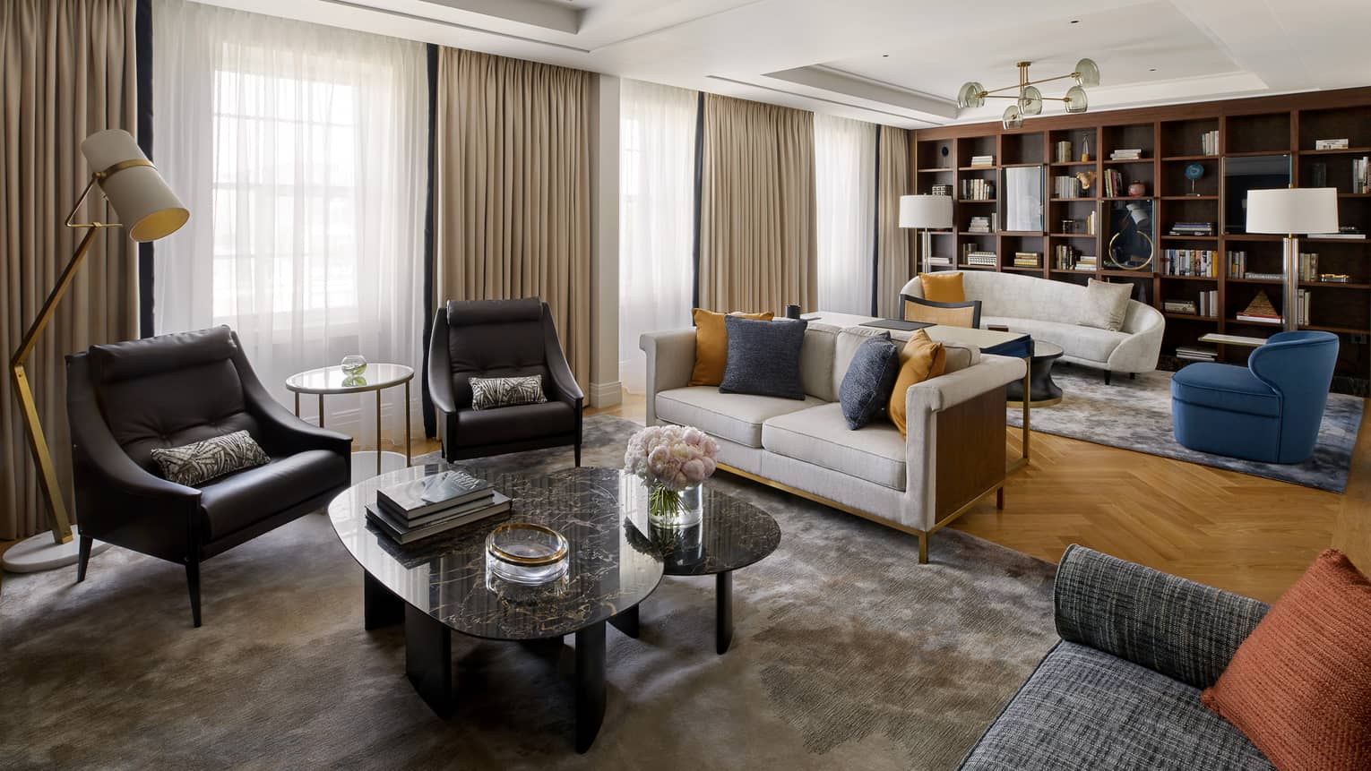 Living area with two black chairs and coffee table, grey loveseat in front of living area with white sofa, blue chair