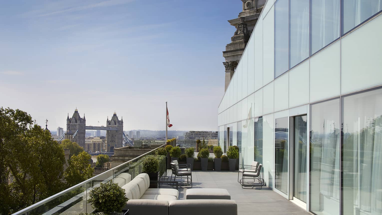 Patio with white sofas under modern two-storey glass wall