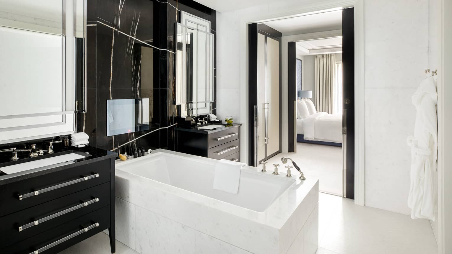 A bathroom with dark furnishing, a tub, two mirrors and two sinks.