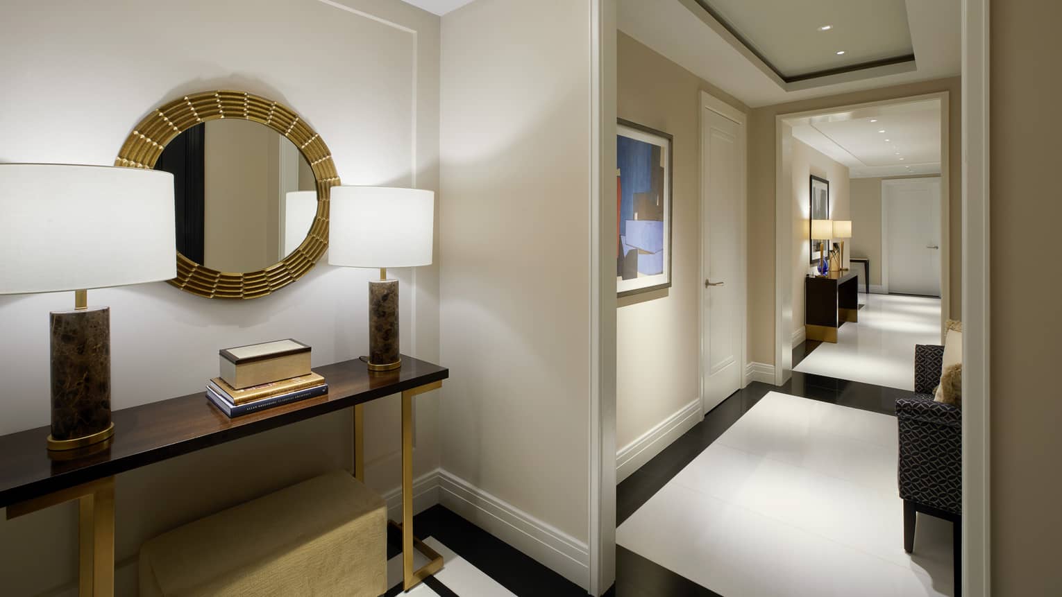 A hallway with lamps, shelves, mirror and art.