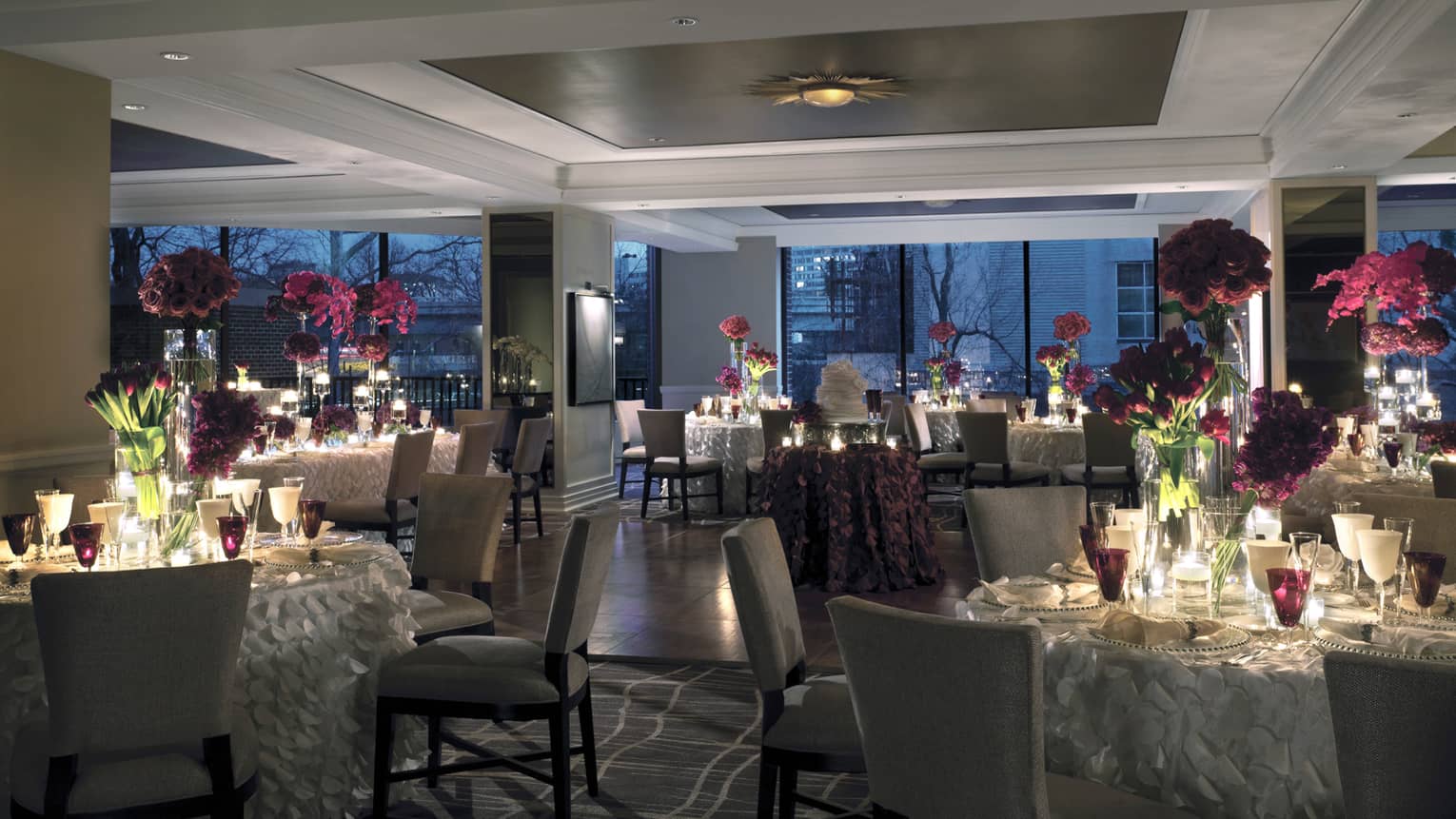 Seasons dining room wedding banquet setting at night with candle-lit tables, fringed tablecloths, floral centrepieces