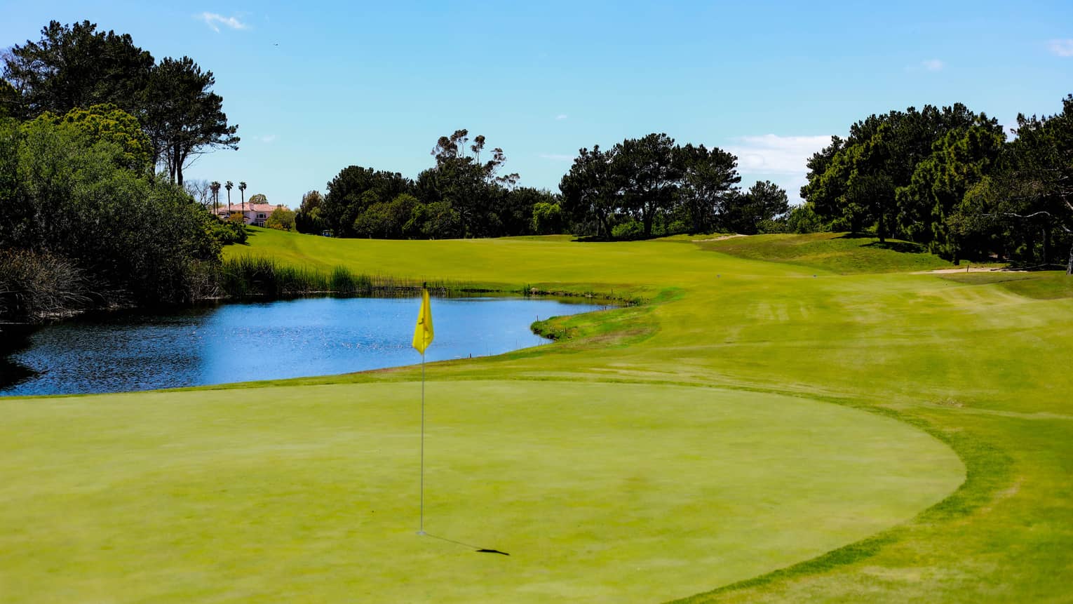A golf course with a putting green and lake
