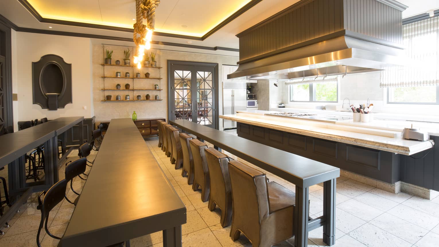 Rows of long tables and chairs face large presentation kitchen space, light fixtures made of rope