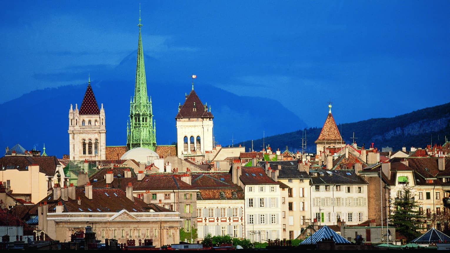 View of historic buildings, towers in Old Town Geneva against blue sky