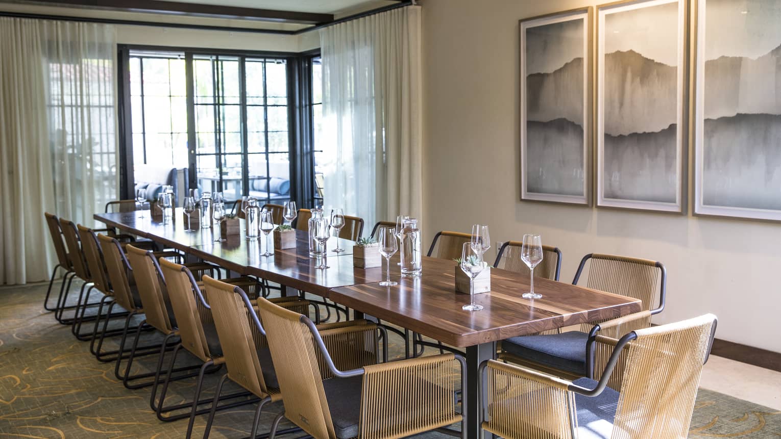 Private dining room with long modern wood table and chairs, wine glasses, corner patio doors