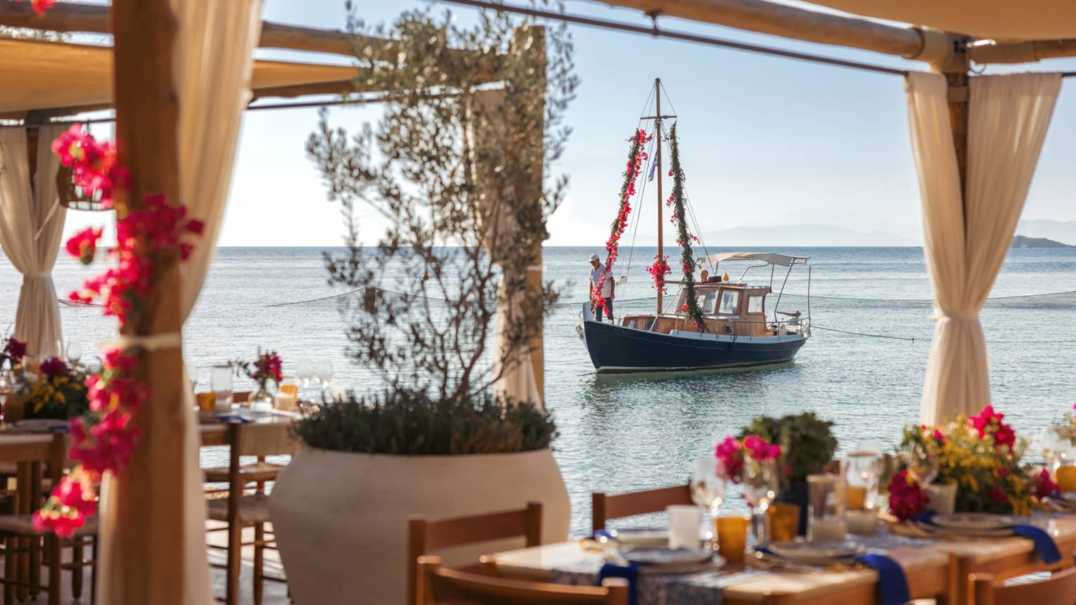 View of sailboat on calm Saronic Gulf through waterfront restaurant patio of Taverna 37