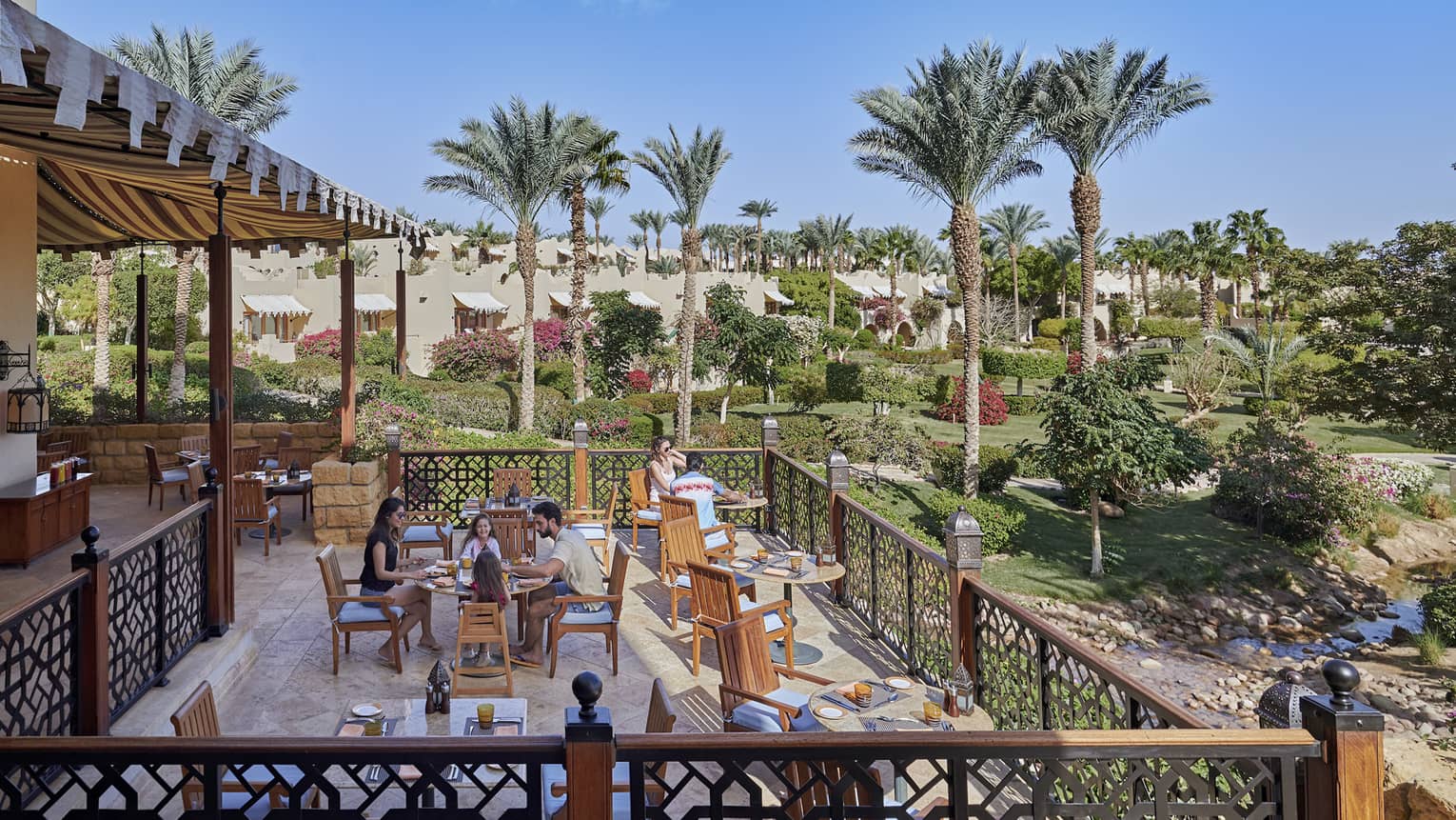 Outdoor restaurant on a wooden deck, overlooking palm trees