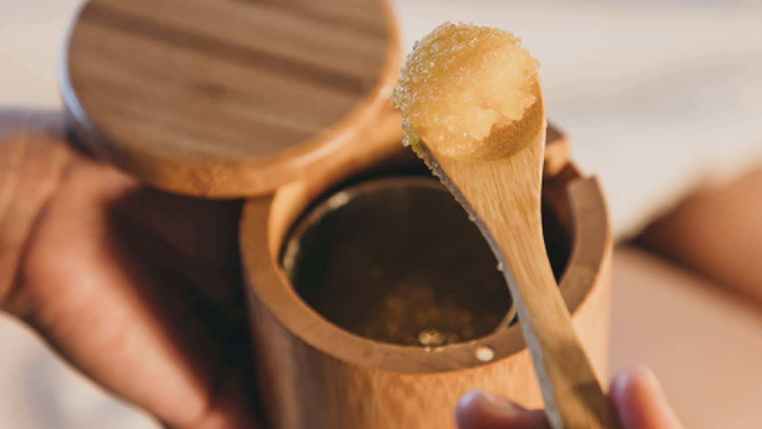 A spa staff member scoops some sugar scrub out of a bamboo container in Hawaii