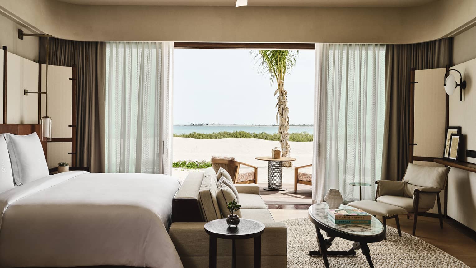 Contemporary bedroom with king bed, sofa, coffee table, arm chair and large walk-out, sea-view terrace