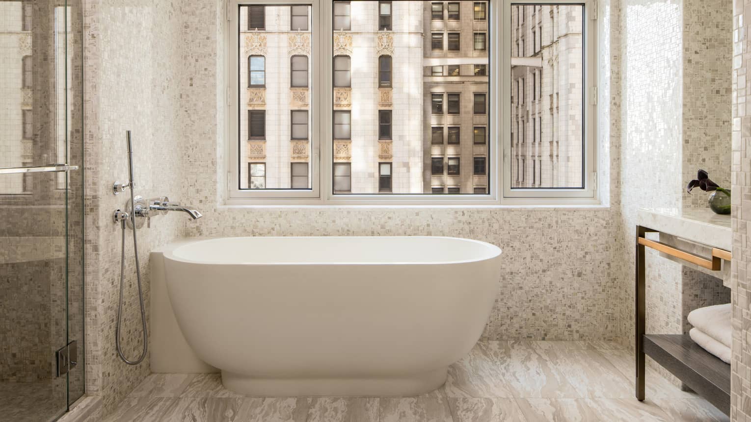 Standalone tub next to a window in a luxury hotel suite bathroom
