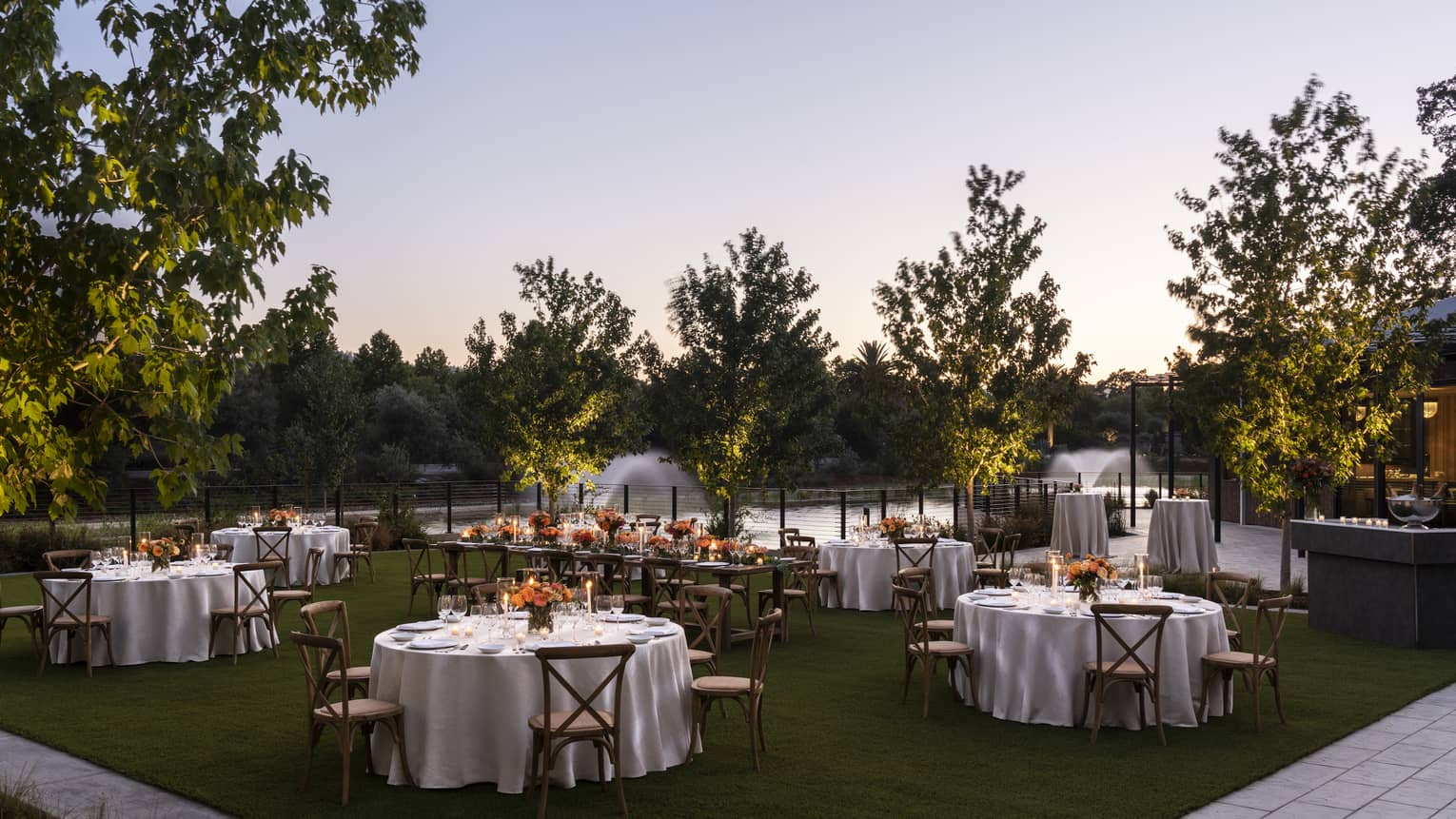 An outdoor meeting area with tables and trees next to water.
