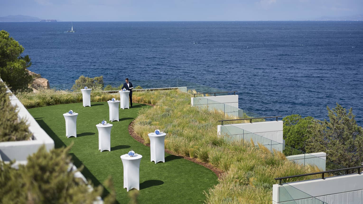 An attendant decorating tables on the Nafsika Platea outdoor event space, overlooking the sea.