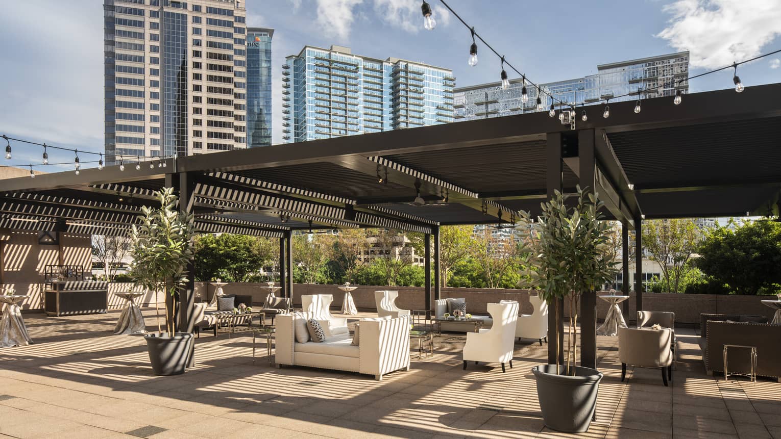 Fifth-floor rooftop terrace during the day with modern white sofas under large wood pergola