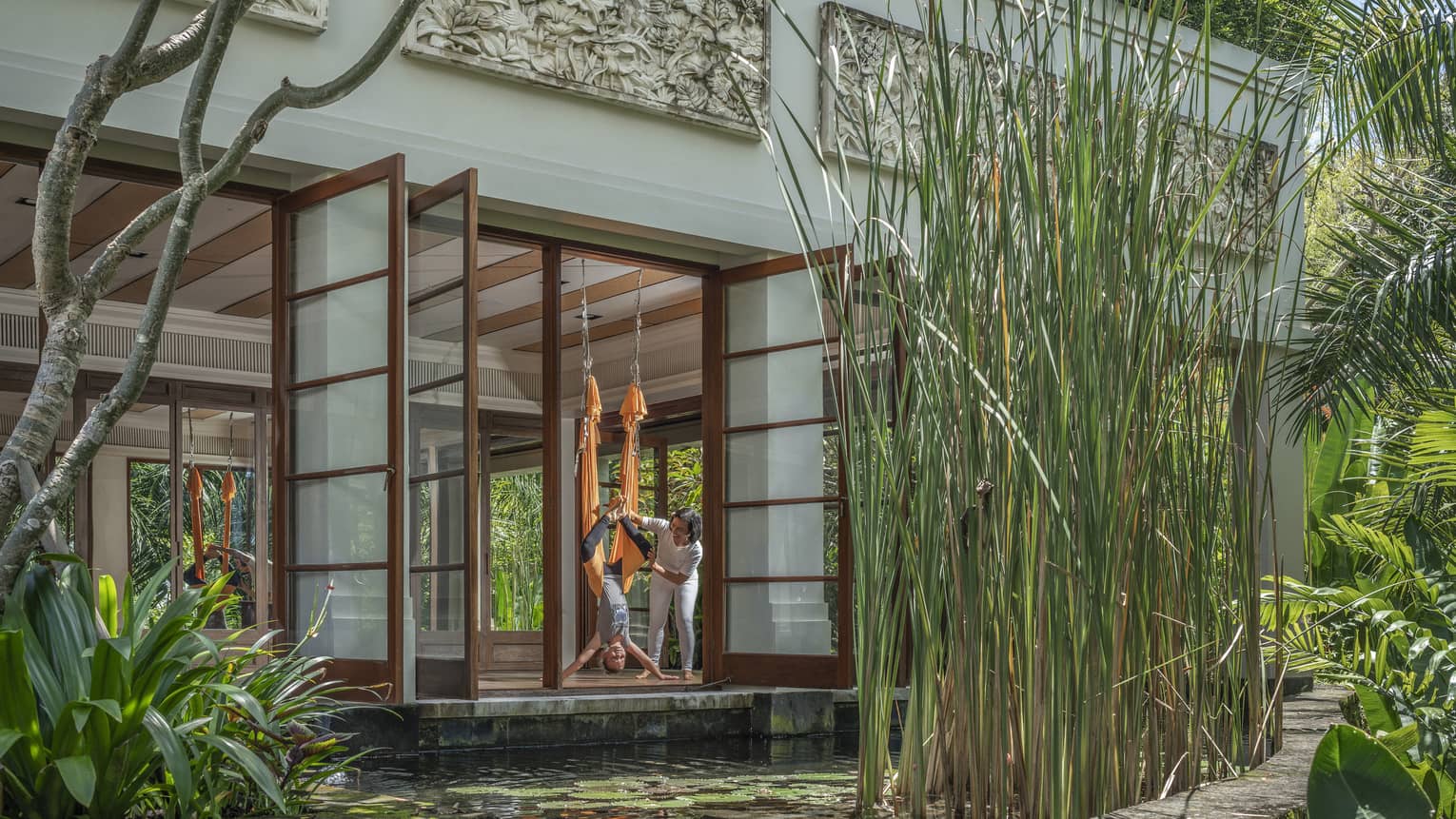 Instructor guides woman in hammock during AntiGravity Yoga session