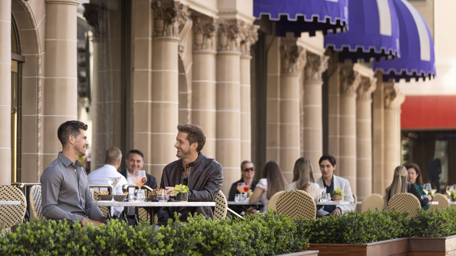 Small groups of people sitting and dining on an outside patio.