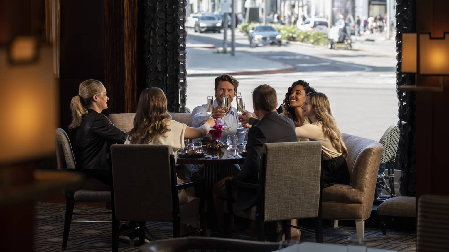 A group of people toasting with drinks at a large table in a dimly lit room.
