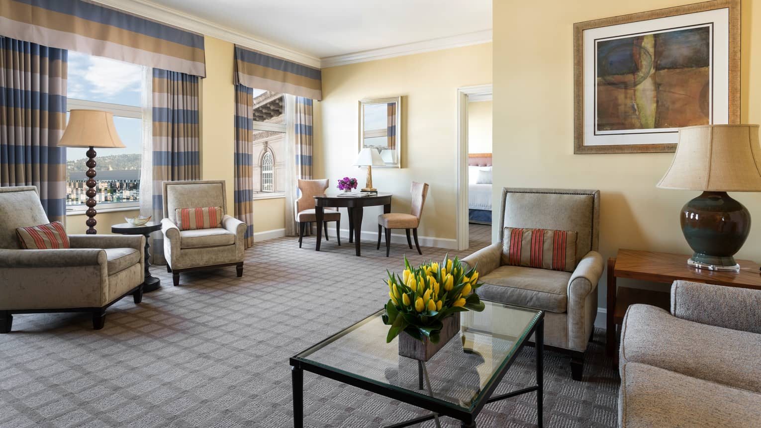 Rodeo View Suite living room, sofas, armchairs, glass table with yellow tulips, striped curtains