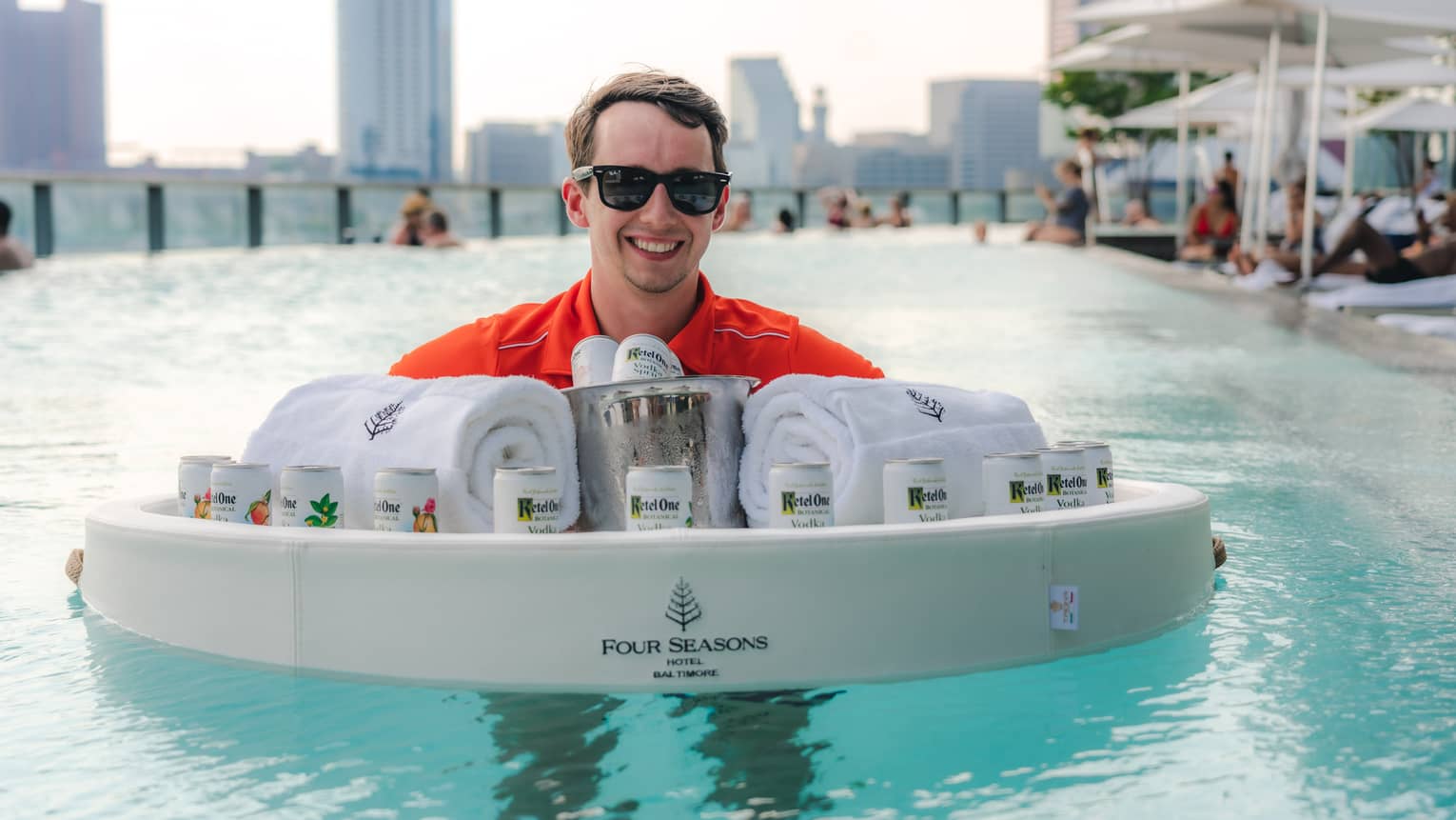 A hotel team member in the pool holding a float with towels and drinks