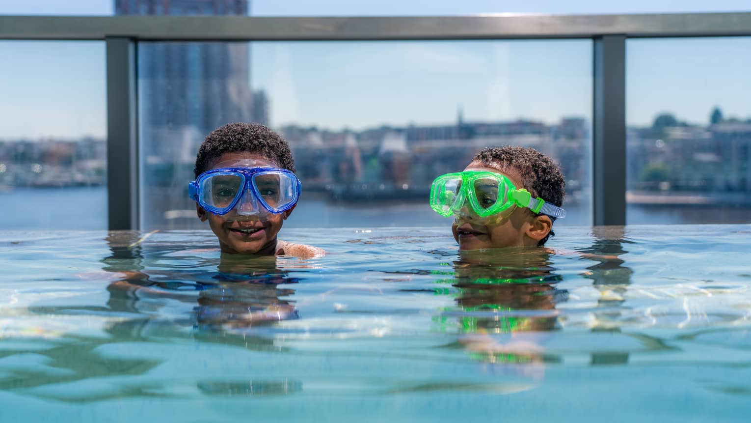 Two young guests wearing goggles and swimming in a rooftop pool