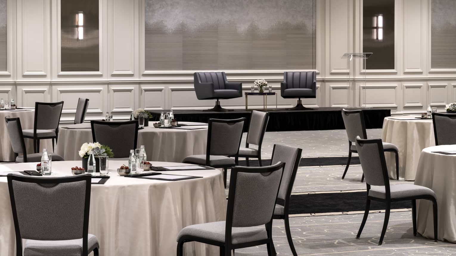 Round tables with white cloth in a large room.