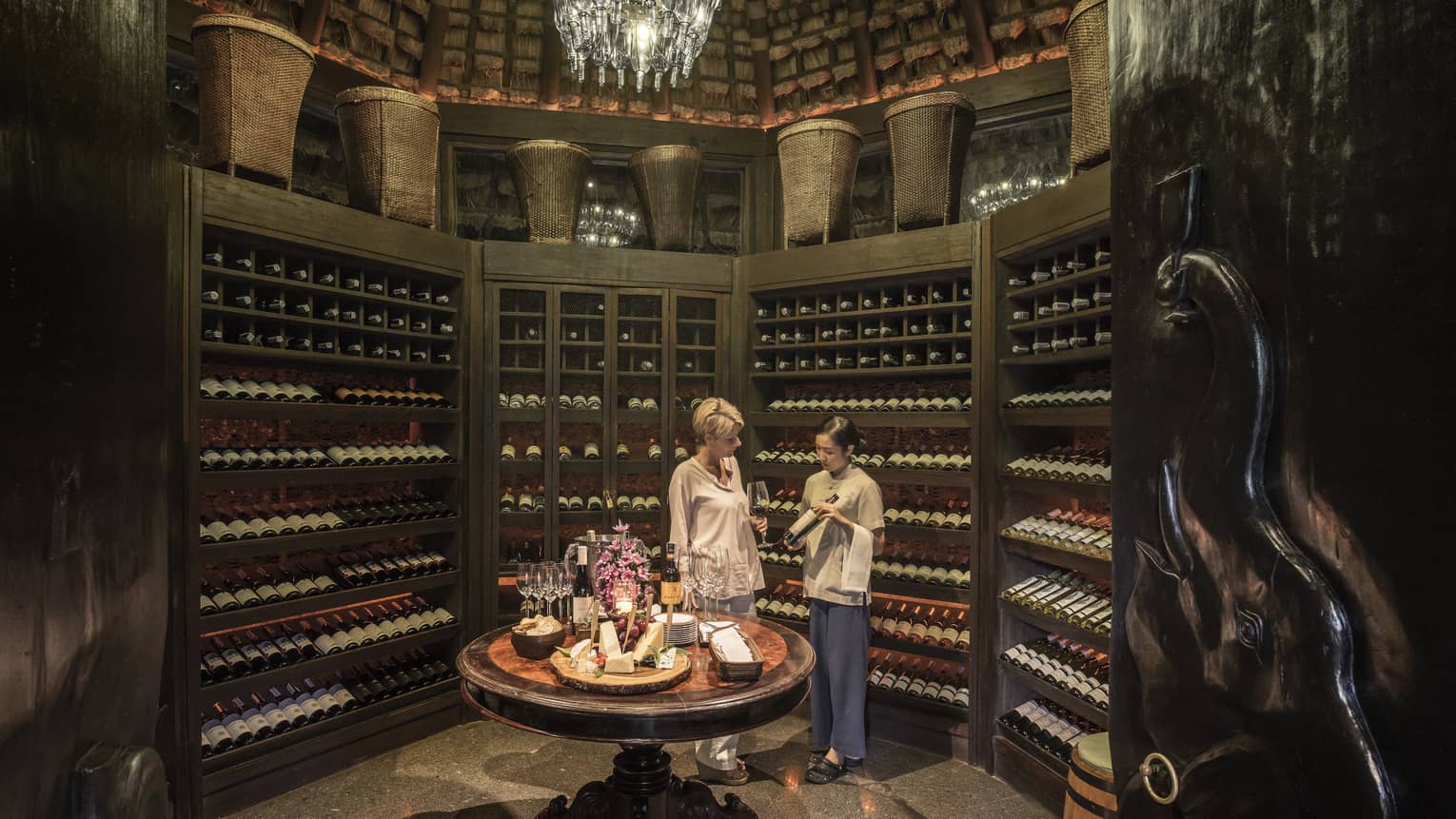 Two people examine wine bottles in Camp Wine Cellar
