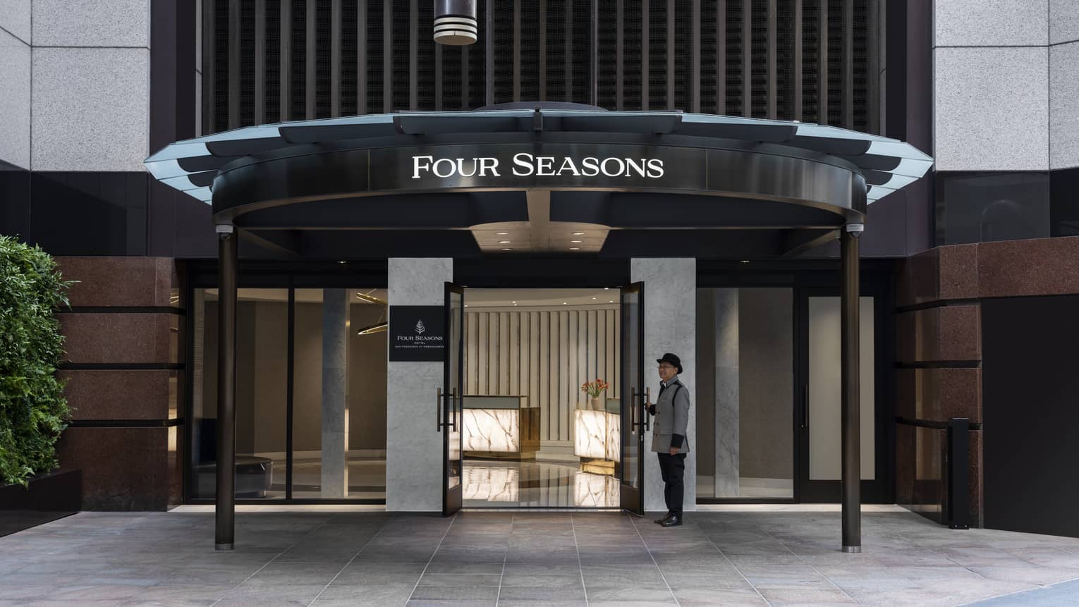 An entrance to a hotel with a team member standing at the door.