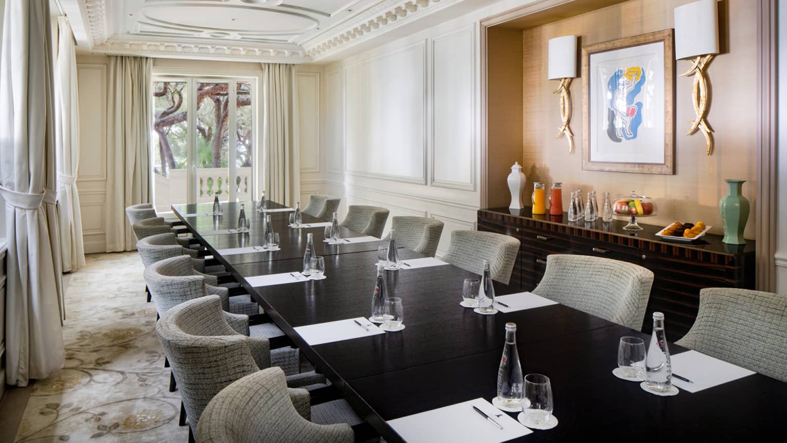 Salon Le Cap with conference table, gray rounded chairs, wood-panelled wall feature with art and sconces