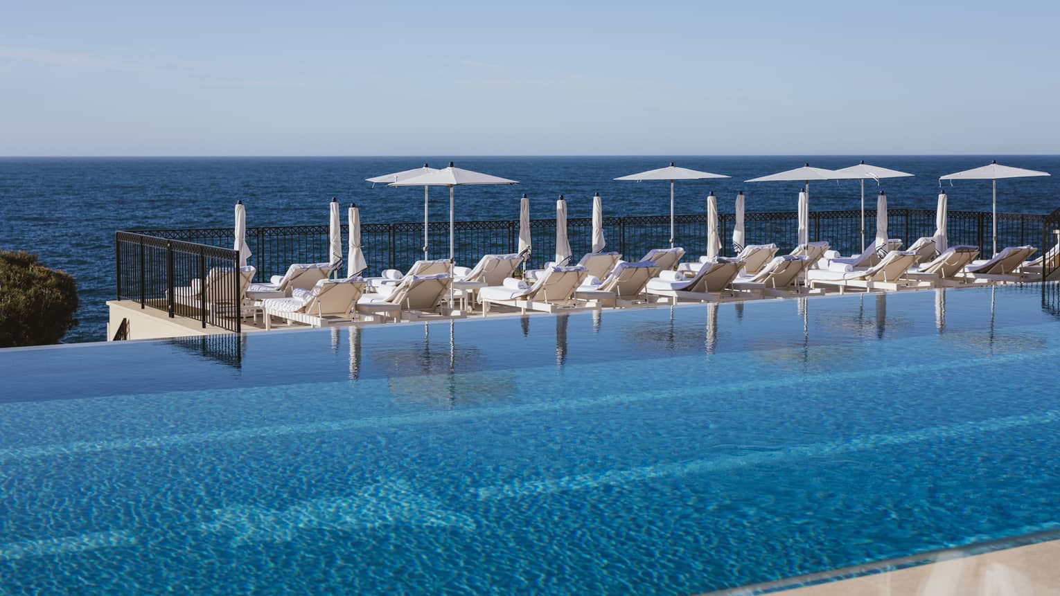 Sun loungers by infinity pool at luxury hotel 