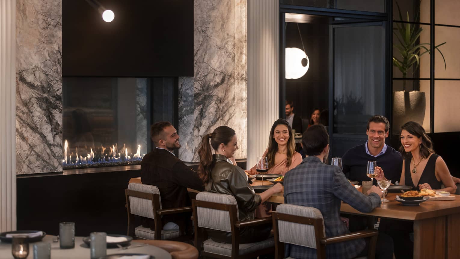 A group of people sitting at a large table in a dimly lit restuarant.