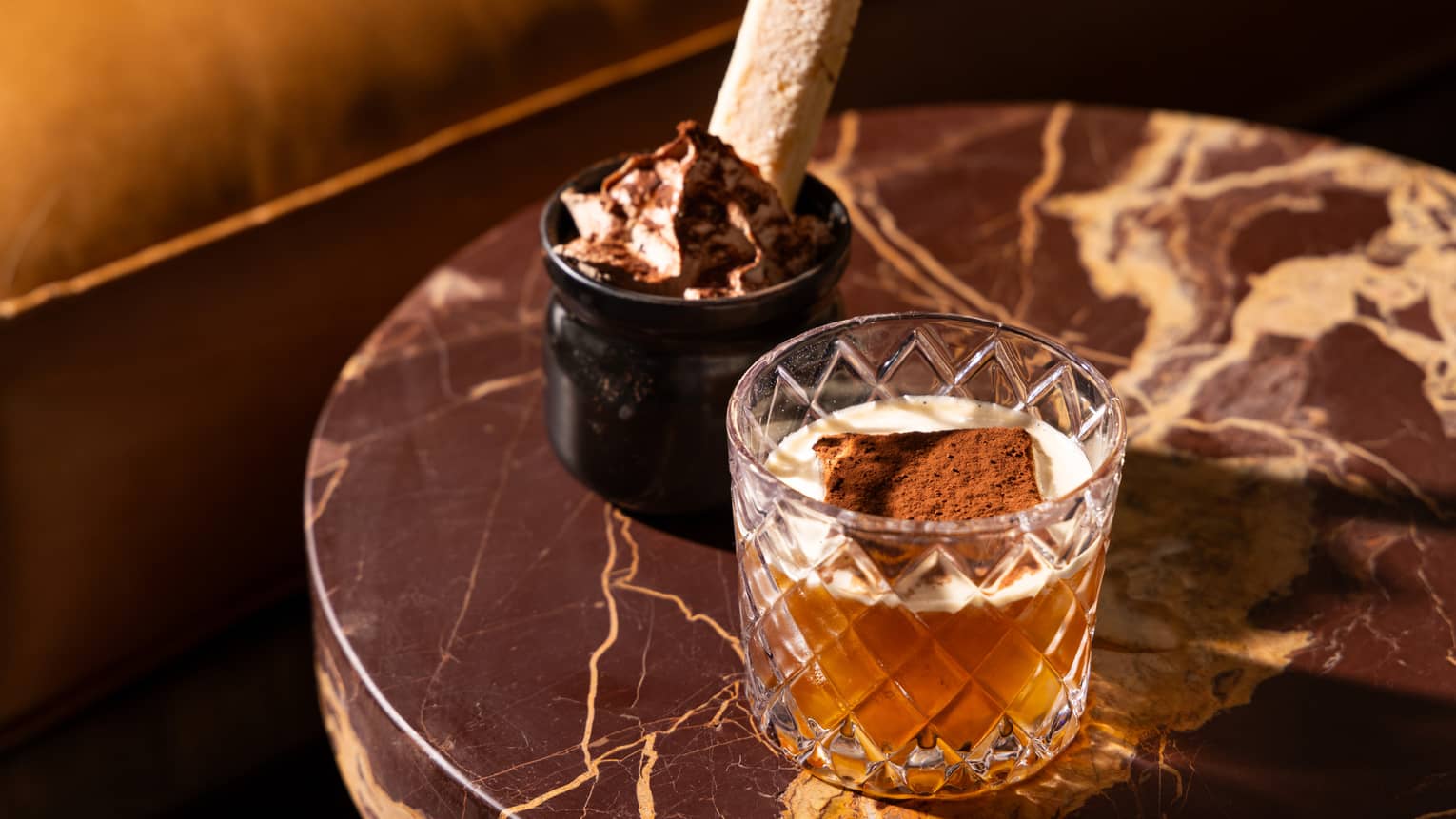 A cocktail next to a tiramisu.