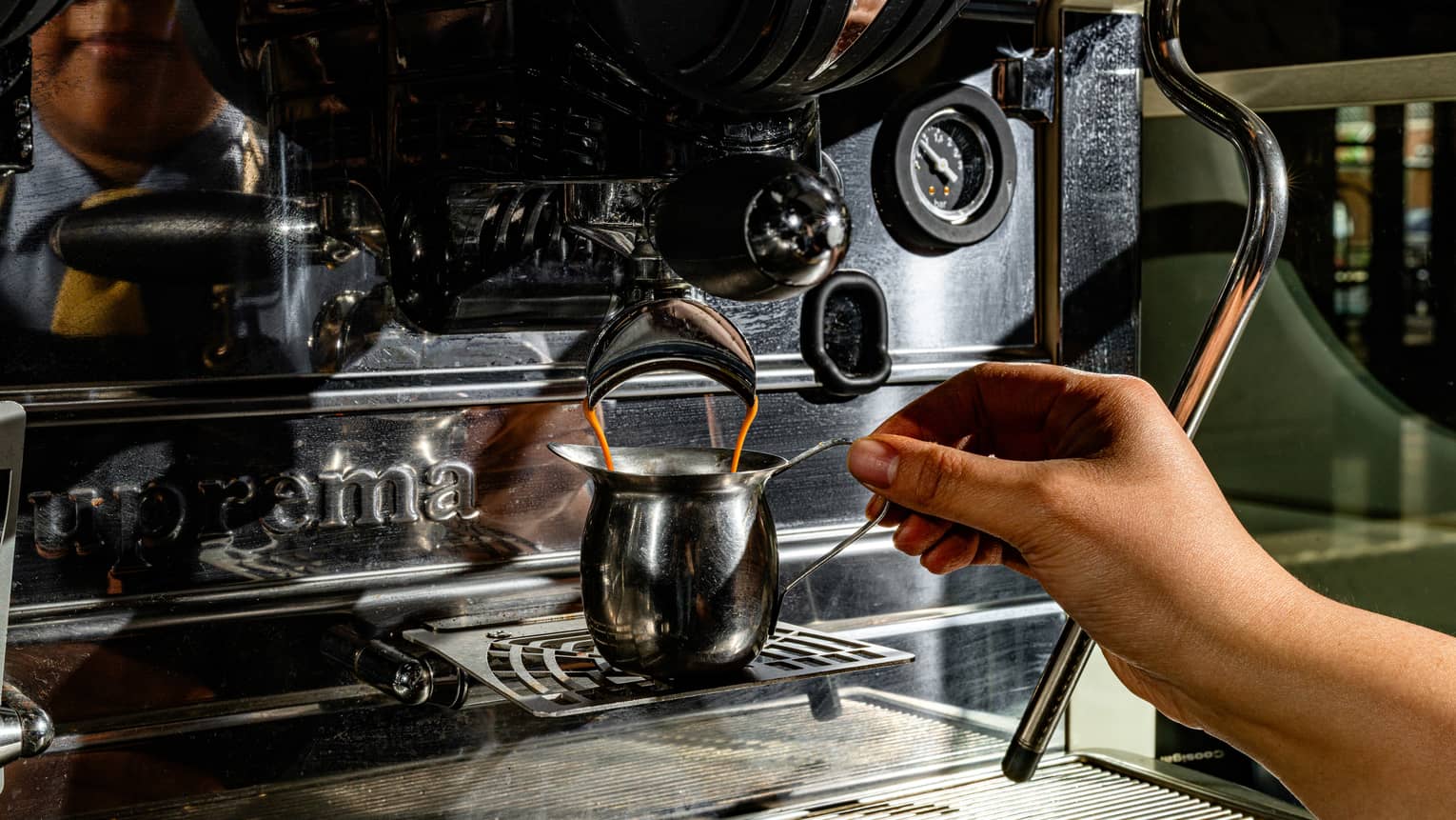 A person filling up a coffee mug at a coffee machine