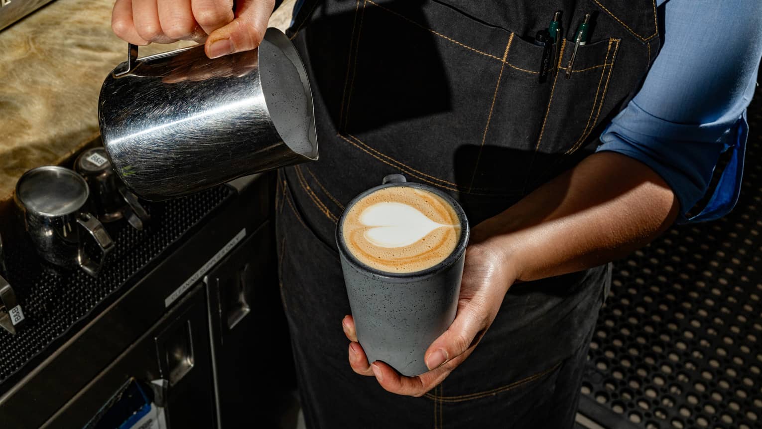 A person pouring milk in a mug of coffee