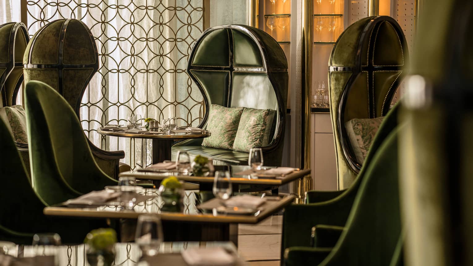 Premier Club booth with dark green leather bucket chairs, accent pillows, decorative brass screen