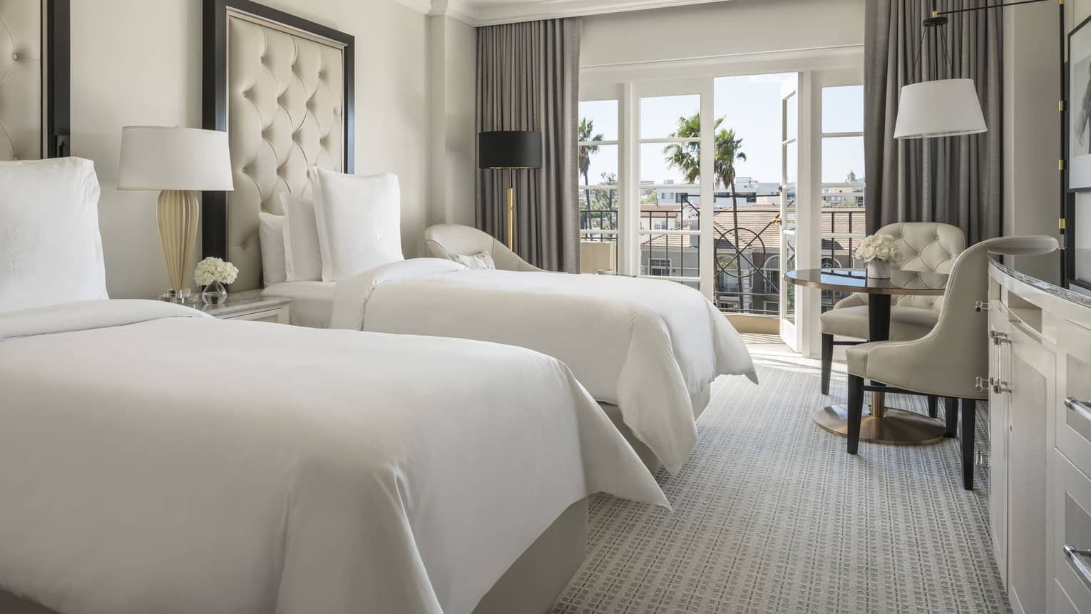 Deluxe Balcony Room two twin beds with tall tufted headboards by cafe table, open balcony doors