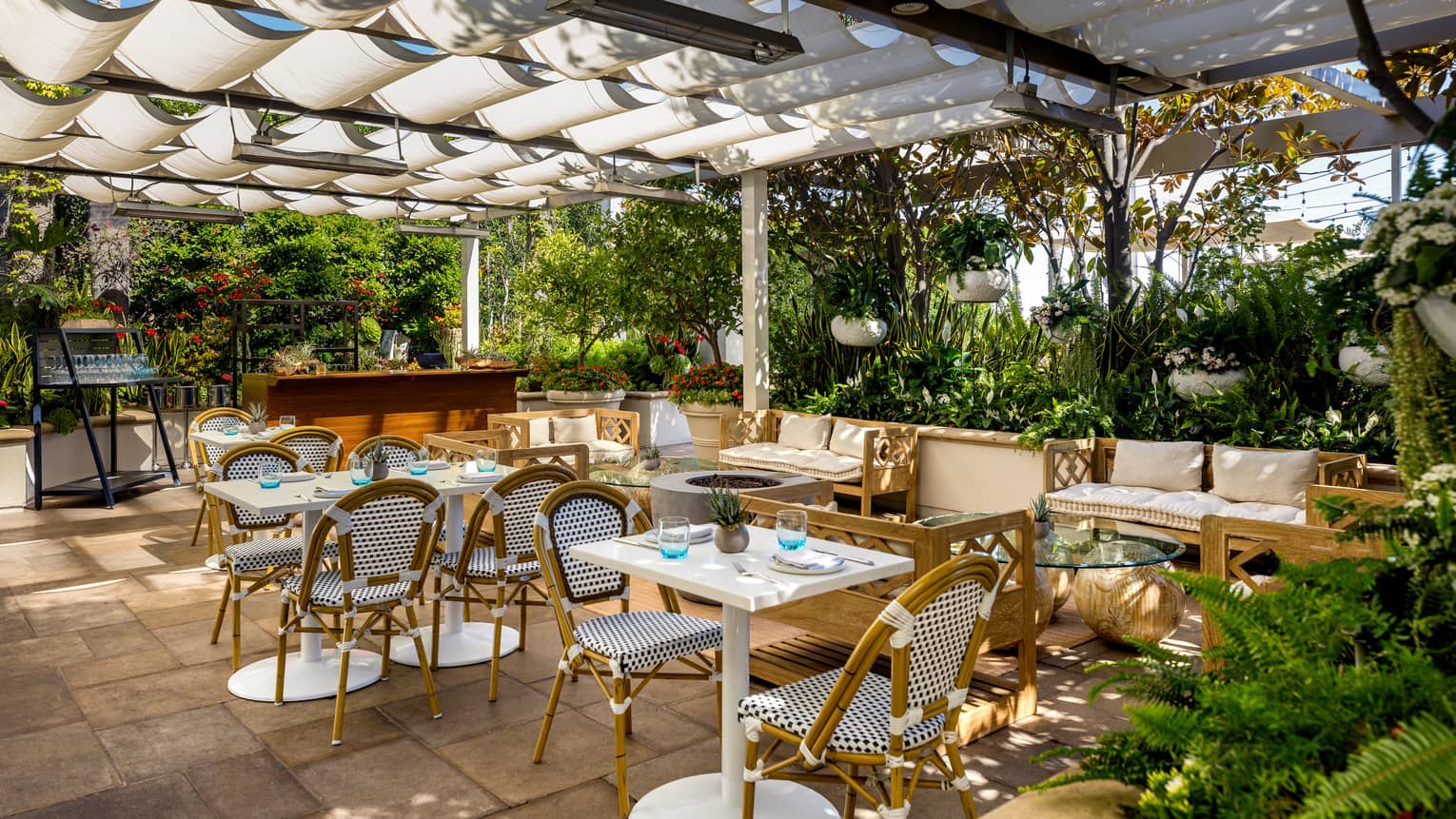 An outdoor covered eating area surrounded by plants.