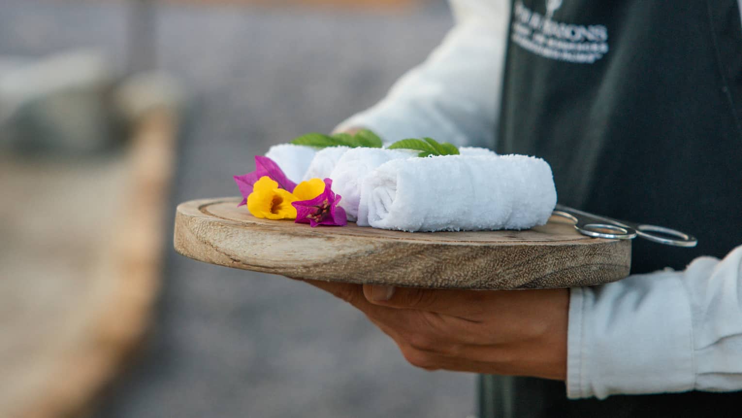 Person carrying a tray with four towels on it.